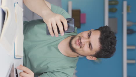 Vertical-video-of-Male-student-chatting-on-the-phone.