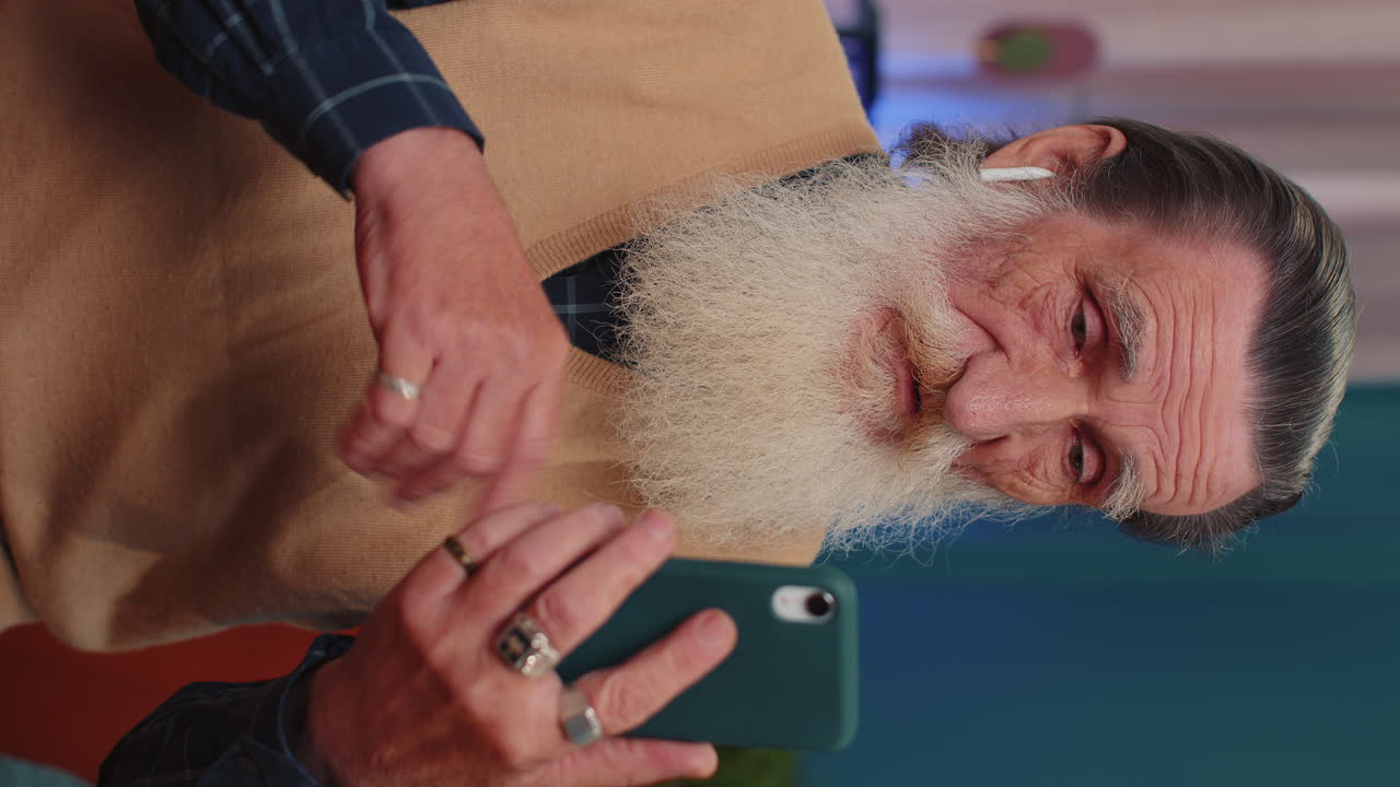 hombre abuelo mayor haciendo una llamada de conversación telefónica con la familia sentado en el sofá en casa en la habitación