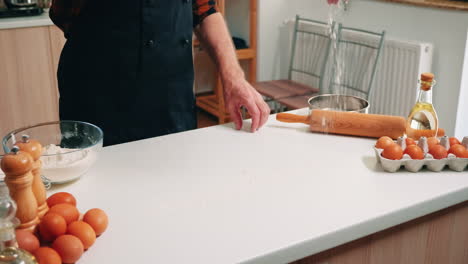 grandfather sieving flour on wooden table