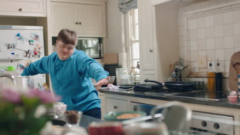 gelukkige tiener met down-syndroom die in de keuken danst, zich vermaakt, een grappige dans viert, het weekend thuis geniet