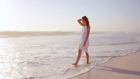 Schöne-Frau-In-Weißem-Kleid,-Die-Bei-Sonnenuntergang-Am-Strand-Spaziert,-In-Zeitlupe,-Roter-Drache