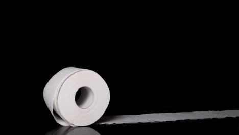 rollo de papel higiénico rodando por la pantalla, fondo negro en cámara lenta