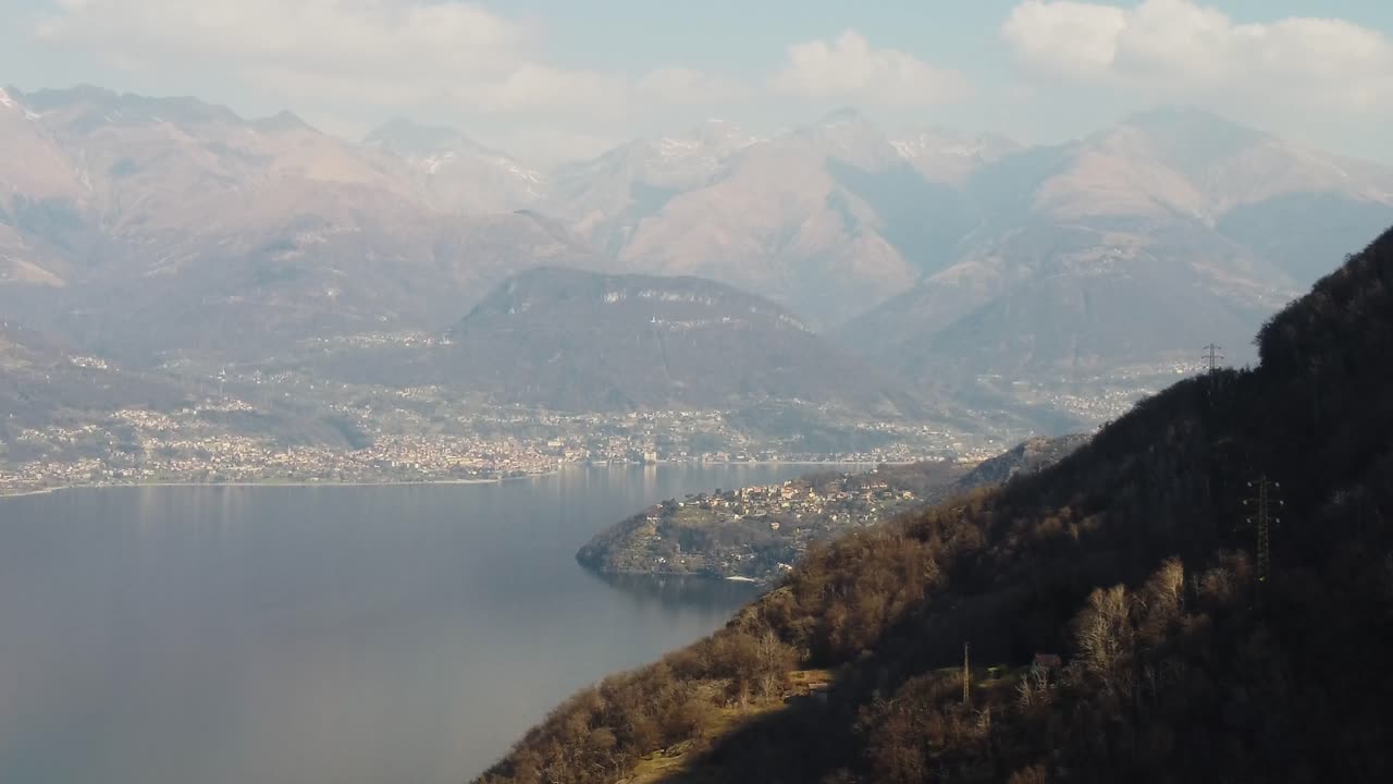 municipio en la costa del lago como con montañas en el fondo, vista aérea
