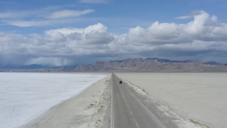 Road-Trip-Concept---Car-Driving-on-Desert-highway-towards-Mountains,-Aerial