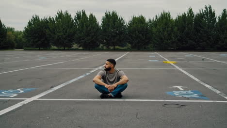 man sitting alone in an empty parking lot