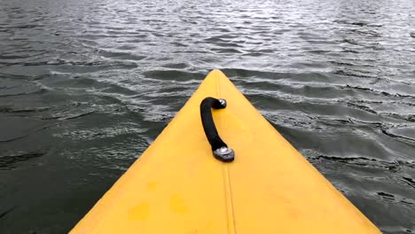 La-Nariz-De-Color-Amarillo-Del-Kayak-Moviéndose-A-Lo-Largo-De-Un-Río-O-Lago-Tranquilo-En-Un-Día-Soleado,-Actividades-Al-Aire-Libre