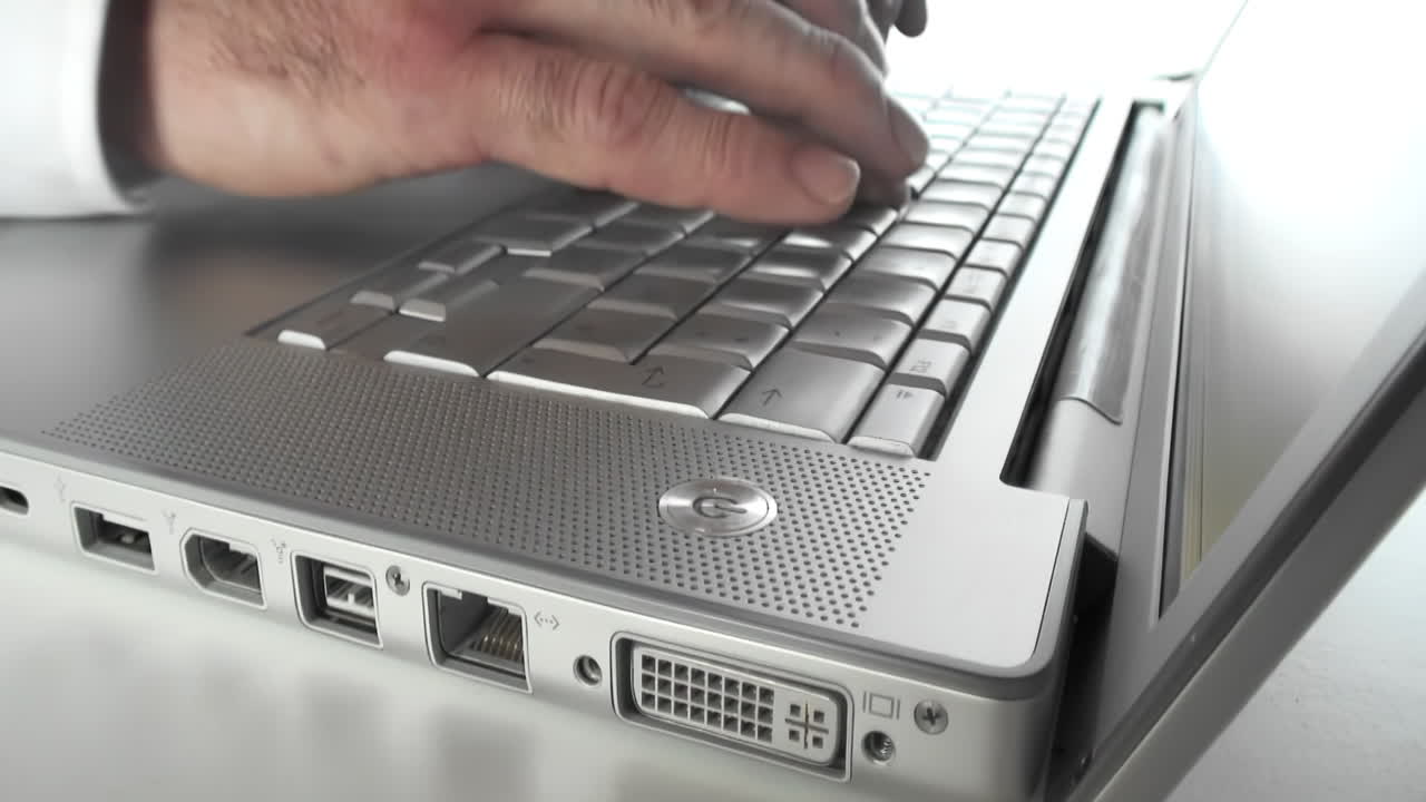 Close-up of businessman working on a laptop sitting at a workplace in business office. Male worker typing on computer, banking, texting a client, chatting online or busy with a project