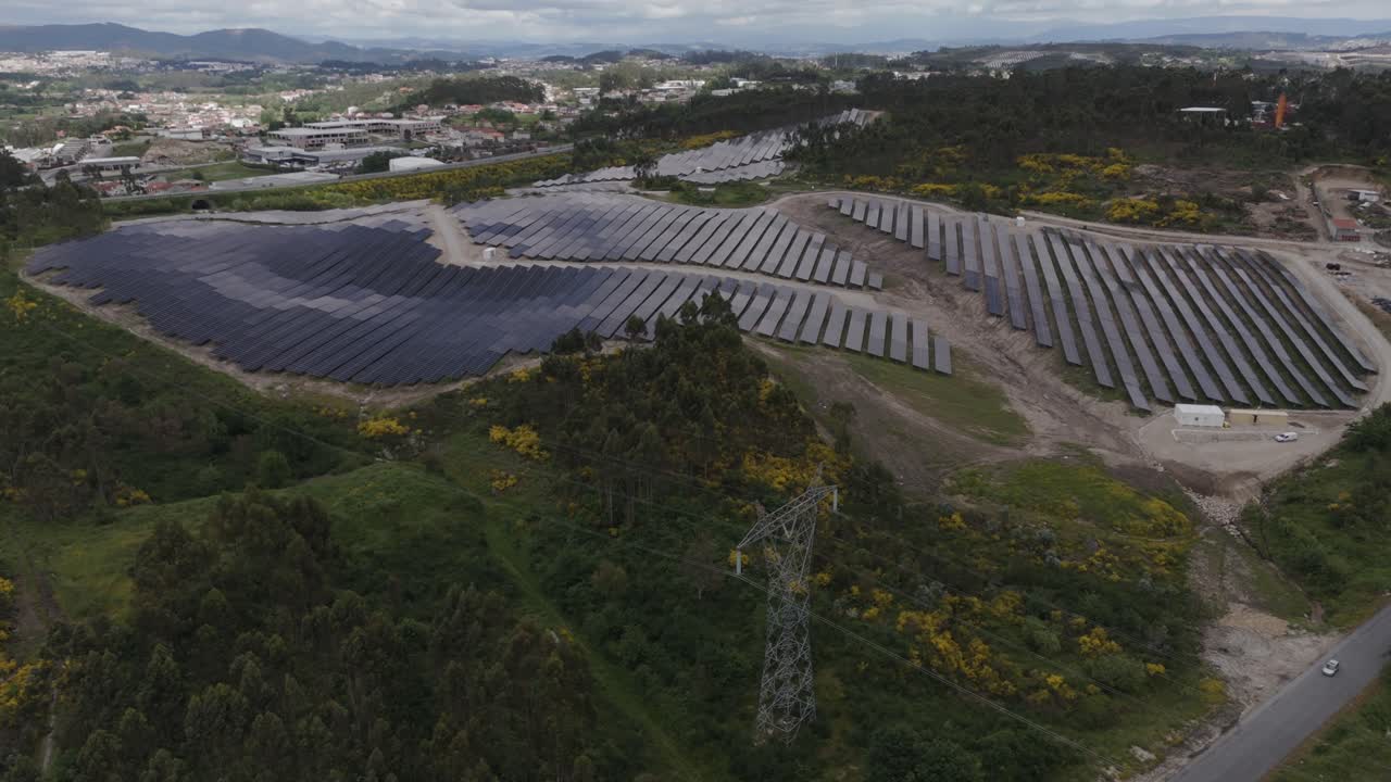 aerial shot of a large solar energy farm with rows of panels bordered by dense forest