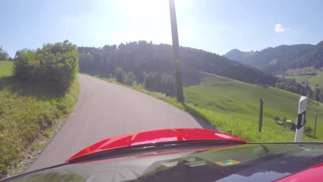 red ford focus drives on a tiny road through the swiss alps