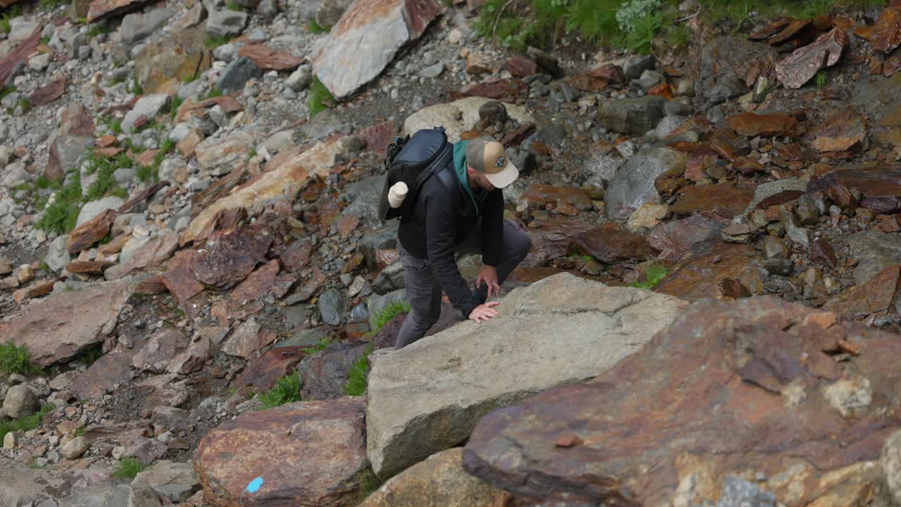 Male Hiker Carefully Climbing Over Rocks In In Valmalenco Region In Italy