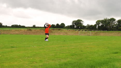 Soccer player practicing on green field under cloudy sky, preparing for game