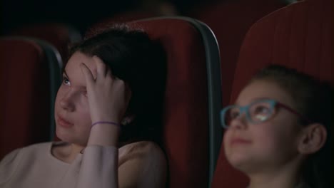 teenage girl watching movie in cinema with younger sister