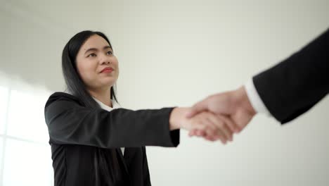 smart asian woman shakes hands to greet a hr staff before a job interview to apply for a job. happy woman seeker or insurance broker presenting a business deal. business woman sending resume.