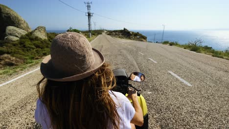 beautiful woman wearing a hat driving an atv on the island , summer time