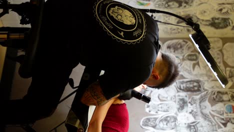 professional tattoo artist working with woman client on a stretcher. vertical