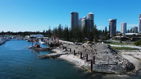 large construction machinery working on the waters edge dredging and removing material to create a man-made harbor