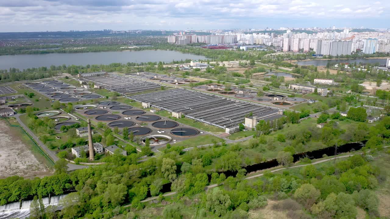 Aerial shot of a wastewater treatment plant and distant skyline. Big city waste processing concept