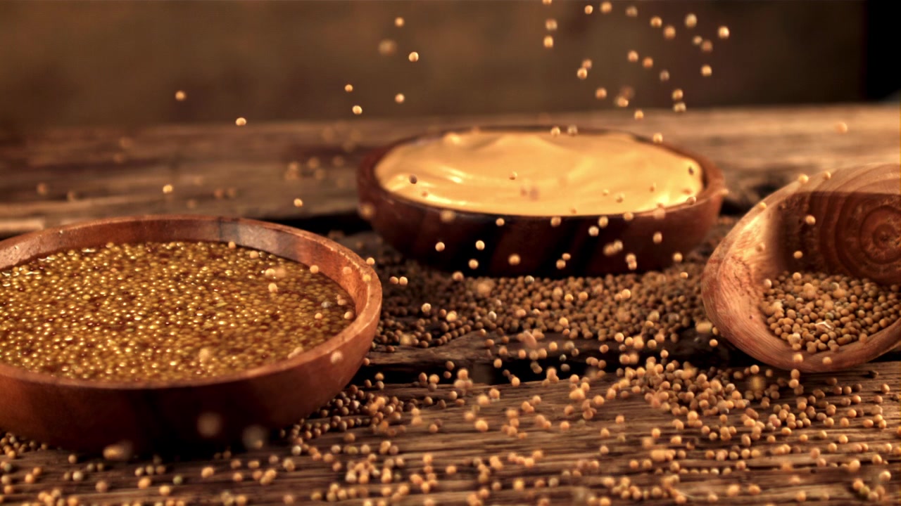 Mustard Seeds Falling onto a Rustic Wooden Table with Prepared Mustard