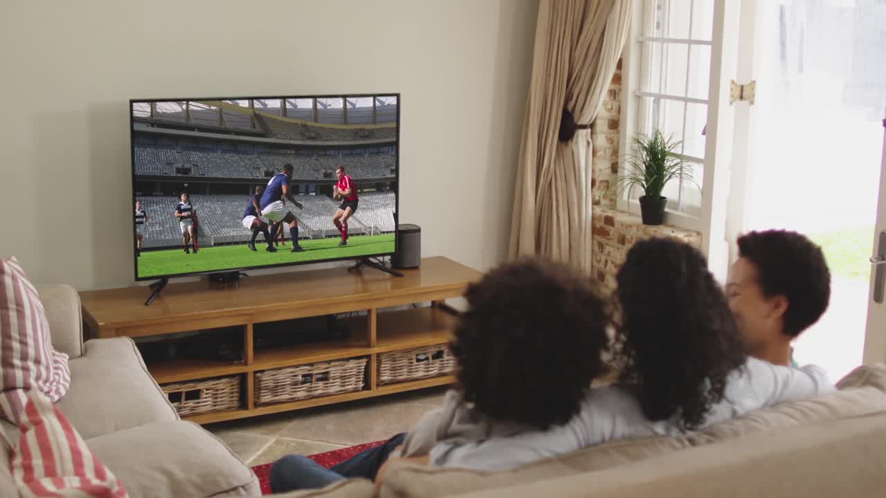 Famiglia felice seduta a casa insieme che guarda una partita di rugby in TV