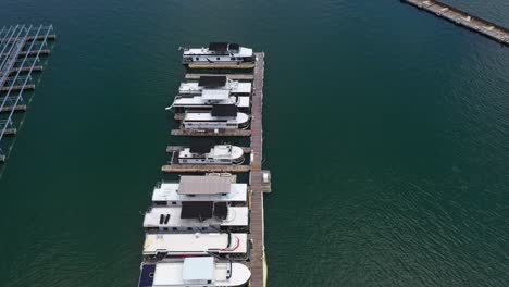 Parkende-Boote-Am-Dock-Des-Lake-Lanier-Und-Grüne-Landschaft-Im-Hintergrund,-Atlanta,-Georgia-–-Drohne-Kippt-Nach-Oben
