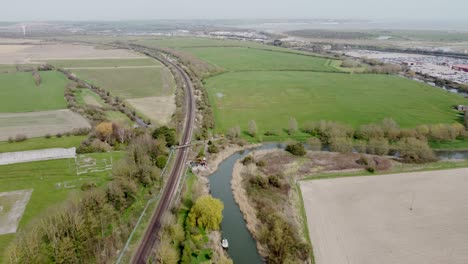 aerial drone shot of train tracks along the river stour in kent, england