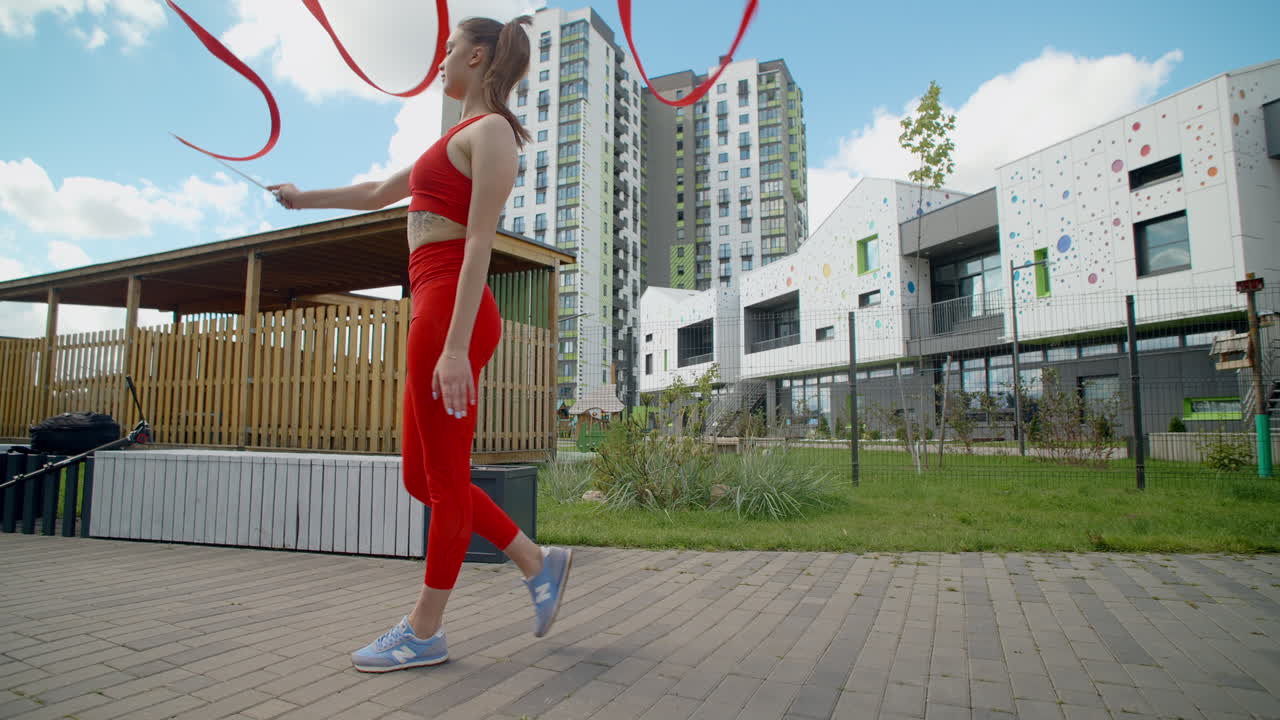 Woman in red performing ribbon dance outdoors