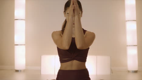 woman sitting in lotus pose on mat indoors. trainer practicing yoga in studio