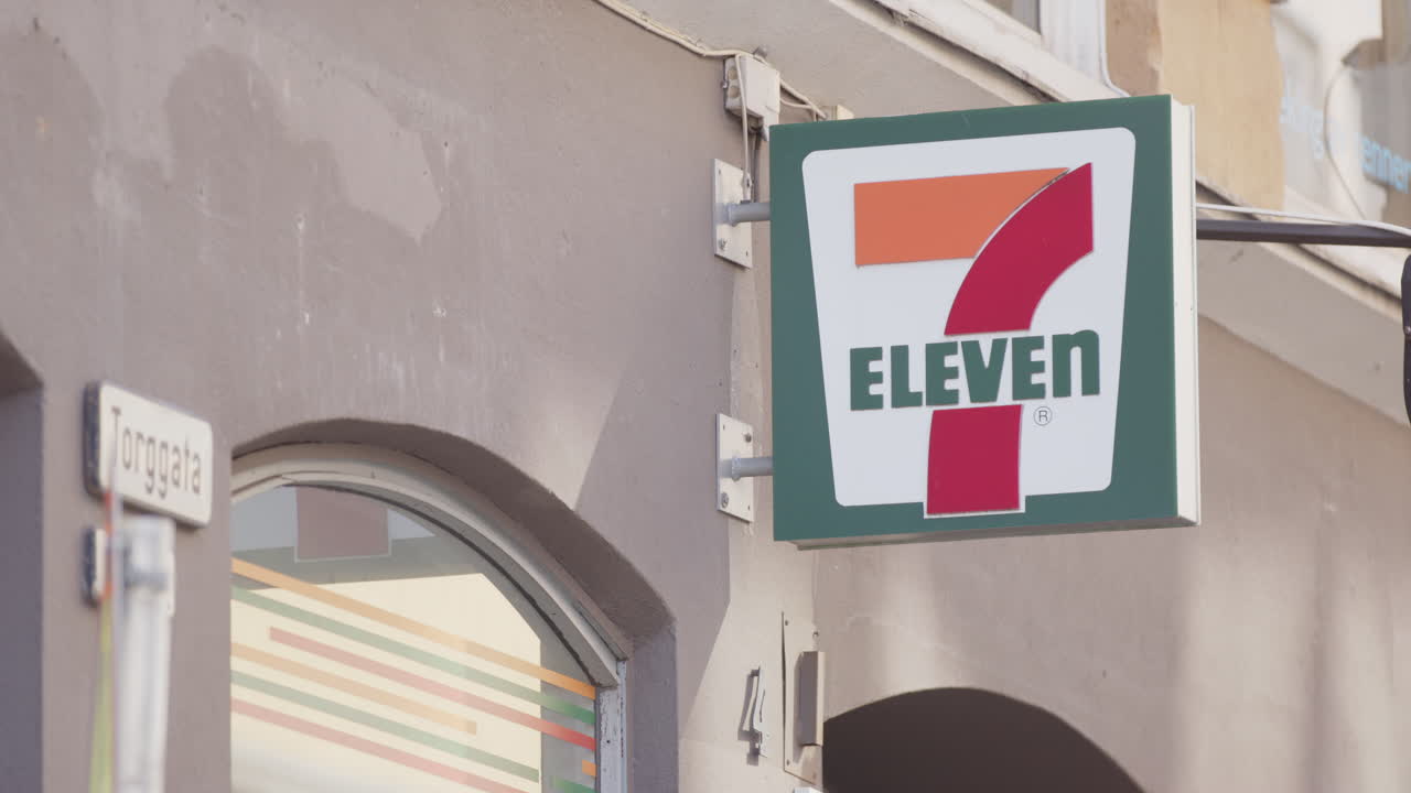 People on the street walk past a 7 Eleven on Torggata street, Oslo, Norway