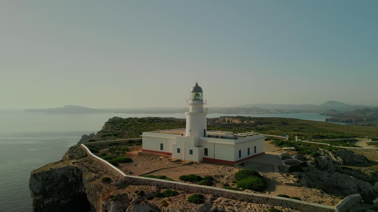 Drone establishing pullback of Cape Cavalleria Lighthouse perched above cliffside on Menorca’s northern tip