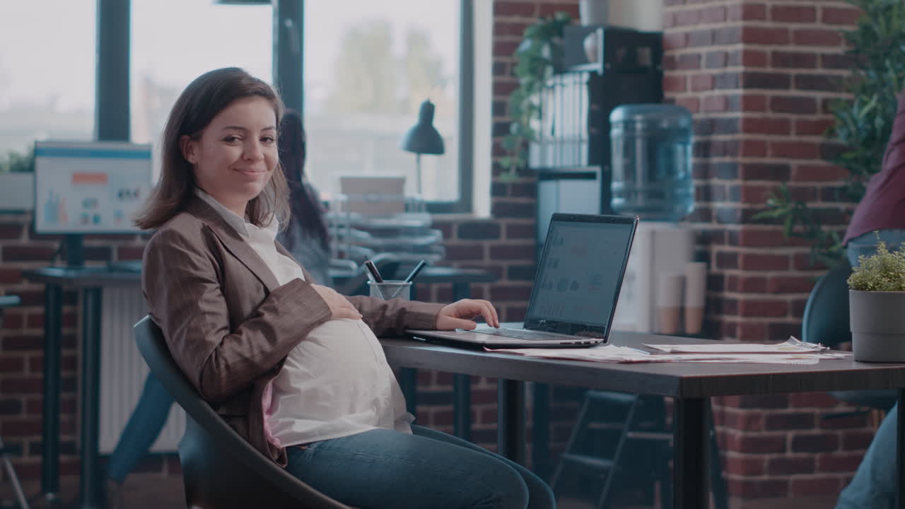 Portrait of pregnant woman working with charts on laptop