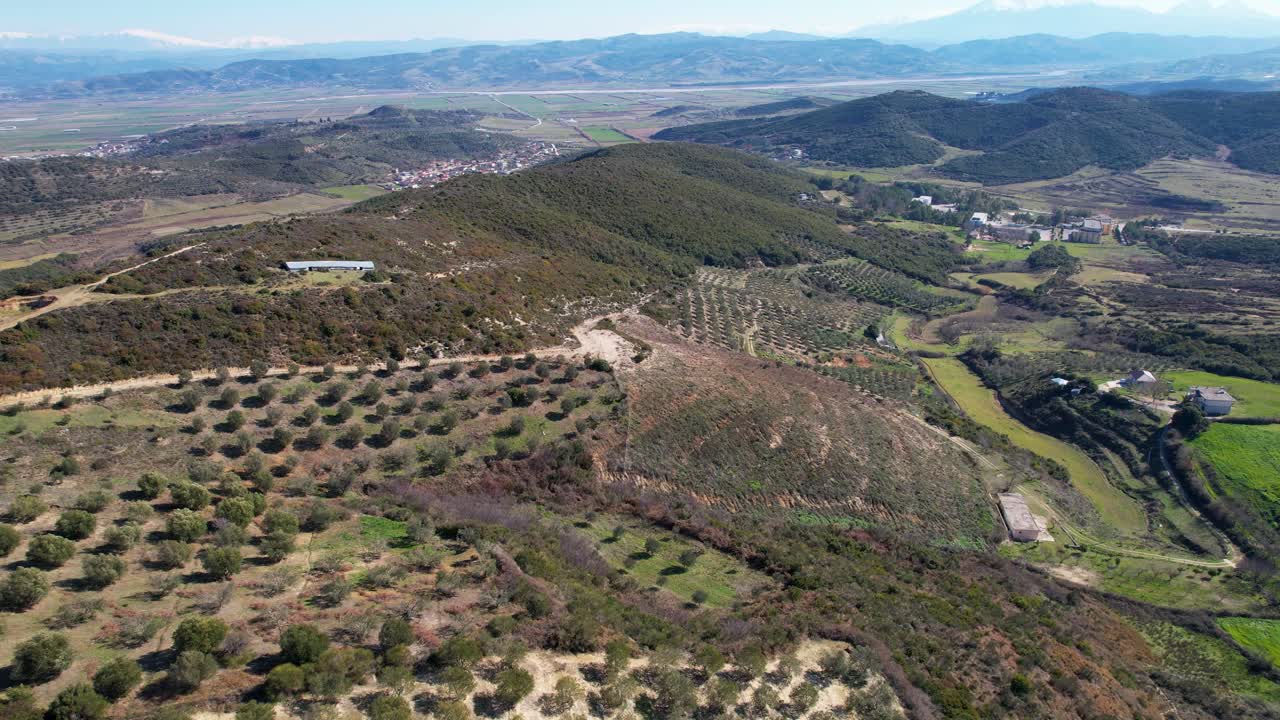 paisaje de campo con colinas y olivos, campos y montañas en el fondo, albania
