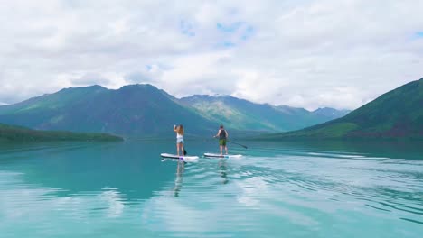 a couple paddle boarding on kenai lake in alaska