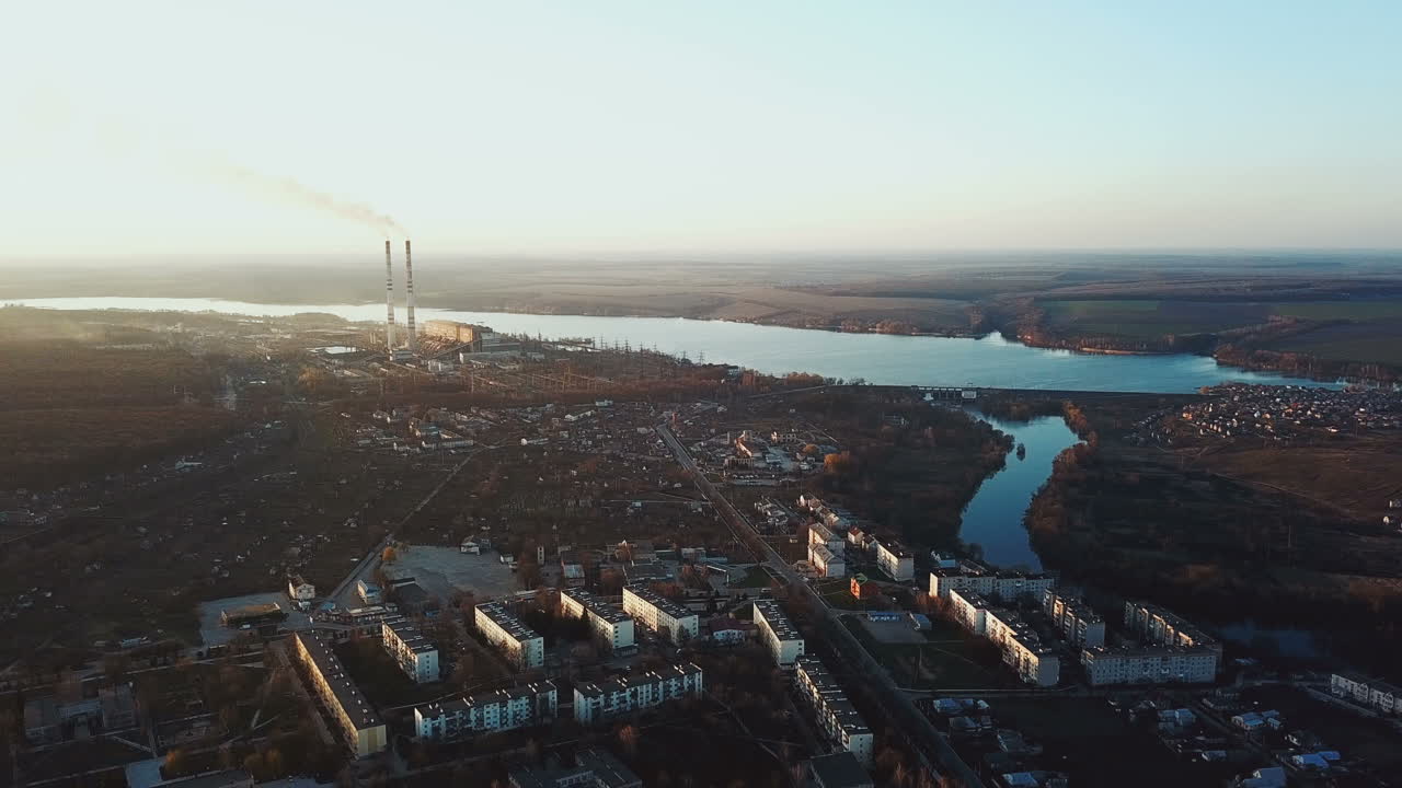 panorama of a small city near the river on the background of a power station in summer. Aerial view