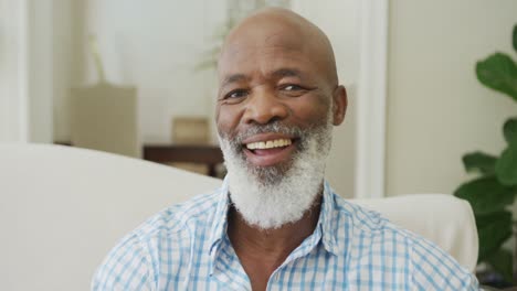 portrait of smiling senior african american man looking at camera in living room