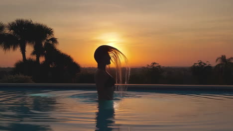 person in a pool at sunset with hair flowing and splashing water