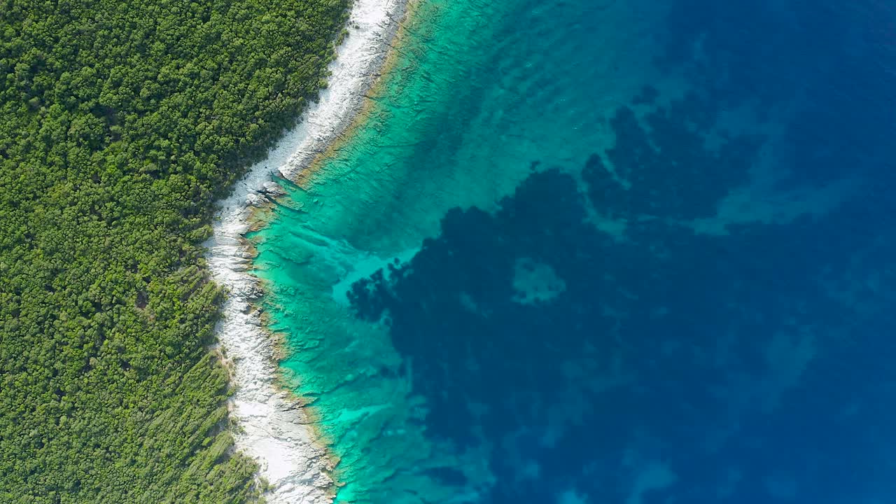 Vy uppifrån längs grekisk ös kustlinje, grön skog och turkosklart hav