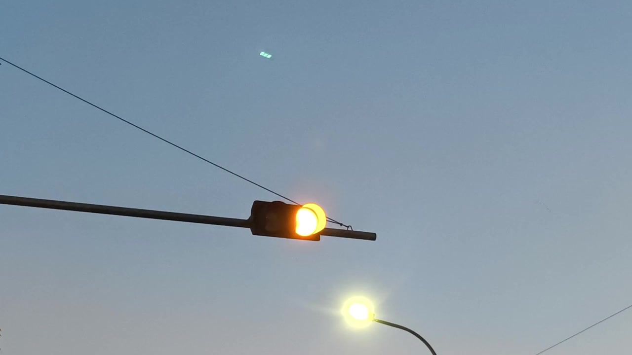 Blikající žlutý semafor proti jasně modré obloze