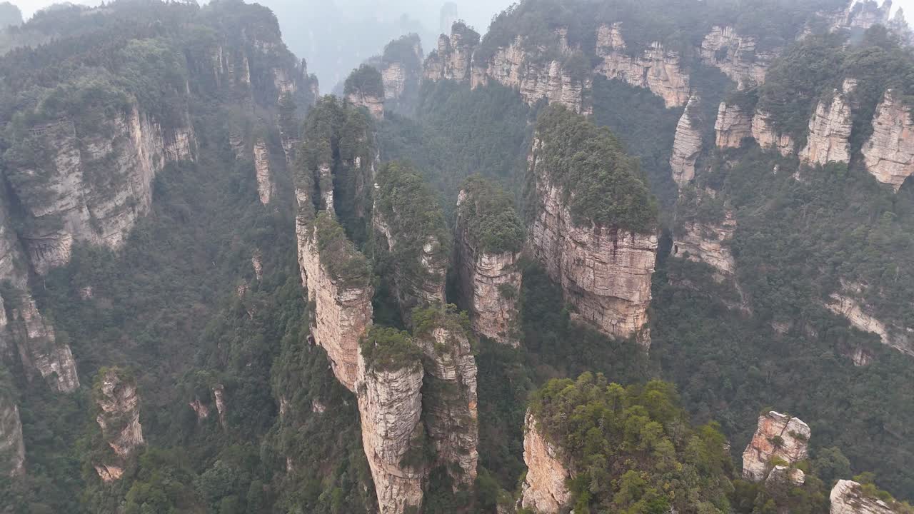 A sweeping drone view over the lush valleys and towering rock formations of Zhangjiajie, China, showcasing the vast and iconic landscape from above