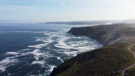 4K-Drone-footage-of-Lands-End-cliffs-with-sea-mist-and-deep-blue-coloured-sea,-fling-backwards