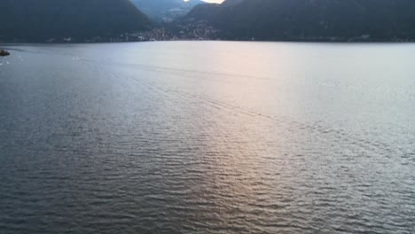 Hermosa-Foto-Aérea-Del-Lago-Como-En-Italia,-Con-Agua-Clara-Y-Pequeñas-Olas-Flotando-En-4k-Mientras-Se-Pone-El-Sol