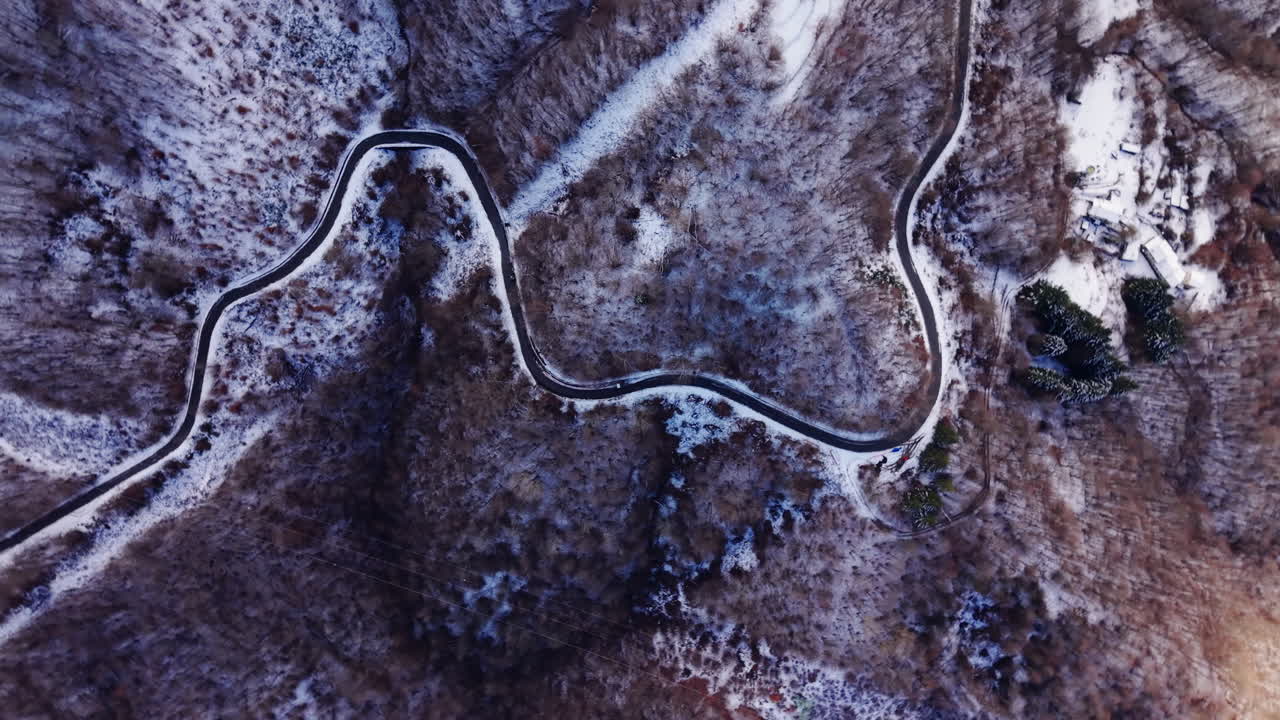 Aerial view of winding snowy road in winter landscape, serene and calm mood