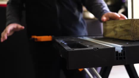 un hombre preparando una mesa y una pieza de madera para cortar con una sierra de mano