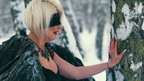 tired woman leans on tree playing phoenix role in forest