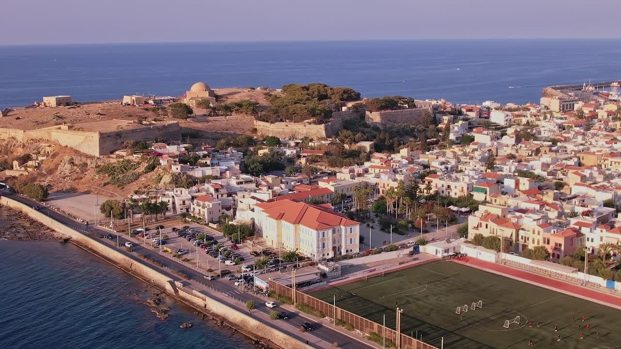 Vista aérea de ciudad costera histórica con fortaleza y campo de fútbol
