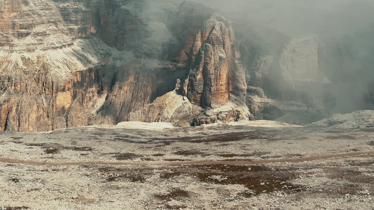 Misty low clouds enveloping rocky peaks , dramatic landscape revealing rugged mountain scenery near Pordoi Pass in Dolomites, Italy