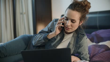 mujer feliz usando teléfono y computadora portátil para trabajar en línea en casa