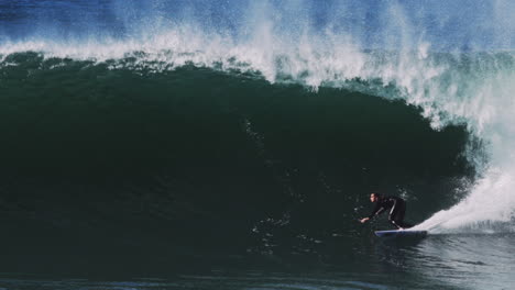 backlit green wave barrels into darkness as surfer glides through foamy chute
