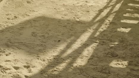 Shadow-of-a-waving-flag-on-beach-sand