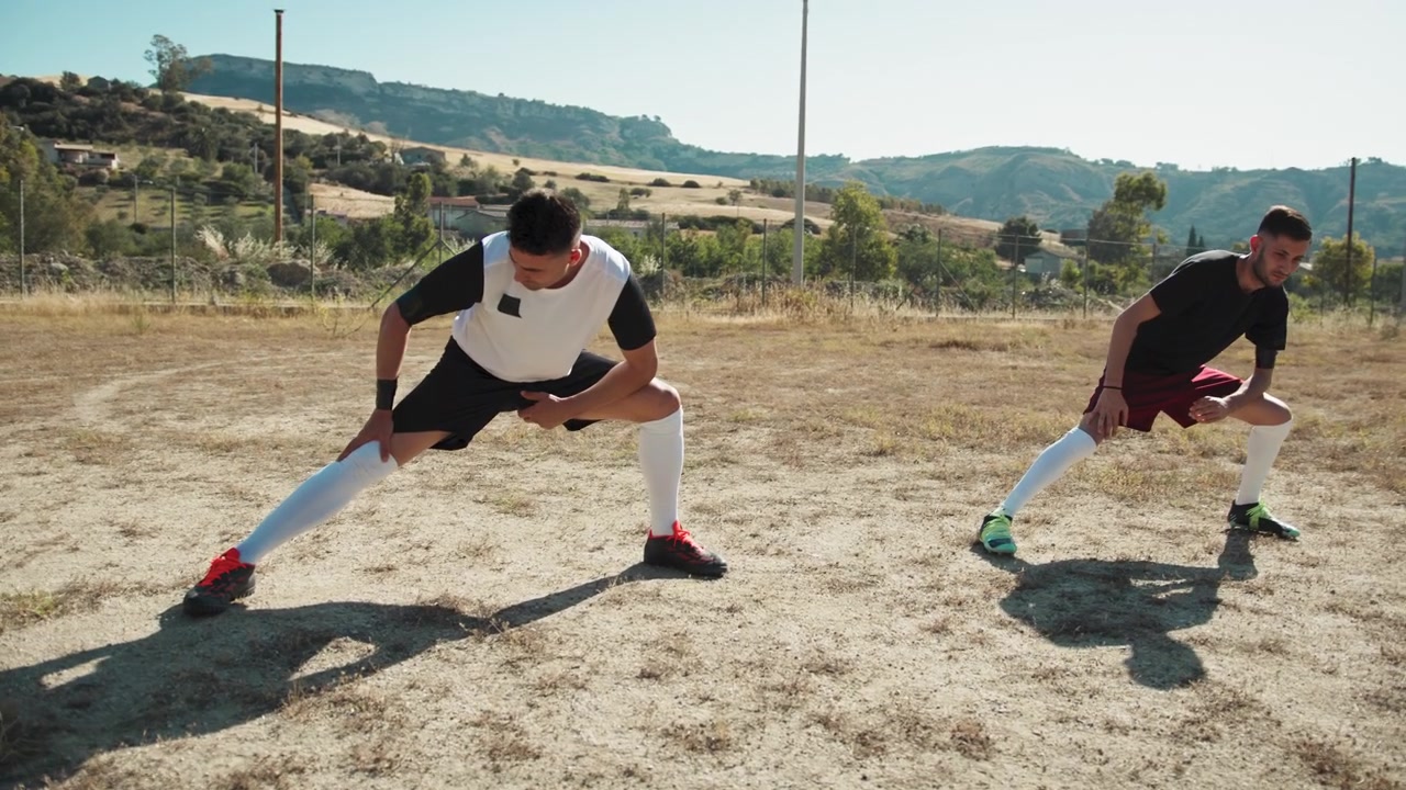Two Foootball Players Stretching Hard Before The Match