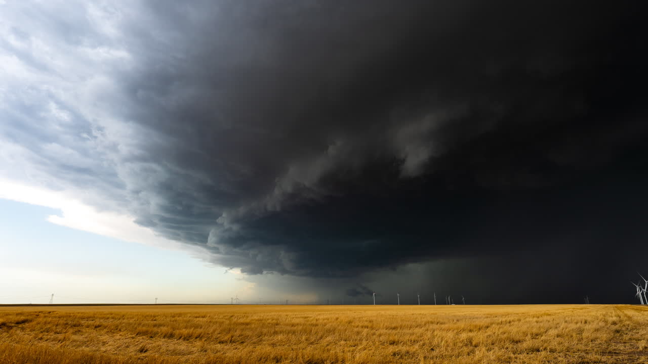 Storm clouds rolling across the sky over warm-colored fields and wind farm